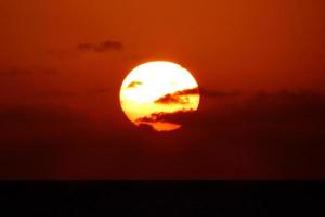zon schijf stijgende lijn over- de horizon van de zee, zonsopkomst, dageraad foto