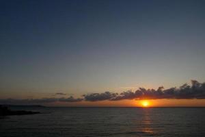 zon schijf stijgende lijn over- de horizon van de zee, zonsopkomst, dageraad foto