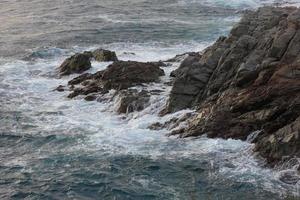 zee bereiken de rotsen creëren spatten van schuim foto