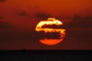 zon schijf stijgende lijn over- de horizon van de zee, zonsopkomst, dageraad foto