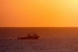 vissers terugkeren van visvangst Bij dageraad na uitgeven de geheel nacht Bij zee. foto