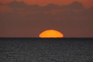 zon schijf stijgende lijn over- de horizon van de zee, zonsopkomst, dageraad foto
