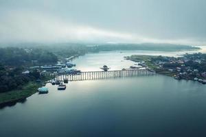 traditioneel ma dorp in ochtend- mistig en houten ma brug in de dam Bij sangkhlaburi foto