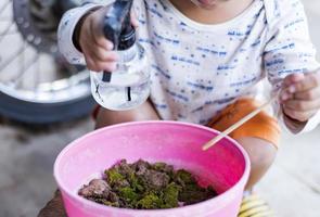 schattig weinig nieuwsgierig meisje aanraken groen mos in buitenshuis doos nieuwsgierig kinderjaren kinderen onderzoeken de wereld in de omgeving van hen. foto