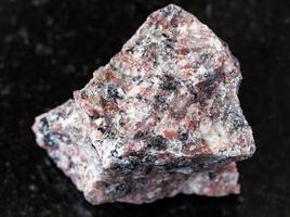 ongepolijst roze graniet rots Aan zwart foto