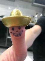 duim, vinger Mexicaans in goud hoed sombrero met geschilderd vrolijk vrolijk gezicht met snorren en ogen foto