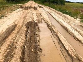 structuur van een vuil slecht aarde weg aarde weg met plassen en klei drogen modder met scheuren en sporen. van de weg af. de achtergrond foto