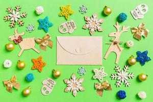 top visie van ambacht envelop Aan groen achtergrond met nieuw jaar speelgoed en decoraties. Kerstmis tijd concept foto