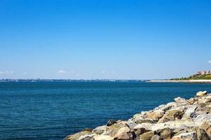 wit stenen strand, rotsachtig strand met een blauw lucht en Doorzichtig water door de oceaan foto