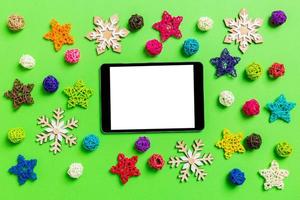 top visie van digitaal tablet. nieuw jaar decoraties Aan groen achtergrond. feestelijk sterren en ballen. vrolijk Kerstmis concept foto