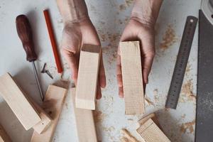 timmerman handen Holding houten planken over- tafel in de werkplaats. foto