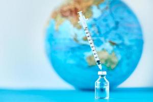 medisch injectiespuit en ampul met een geneeskunde tegen aarde wereldbol foto