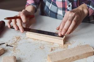 timmerman handen nemen meting met een potlood van houten plank. foto