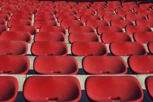 leeg plastic rood stoelen in buitenshuis theater in zonnig dag. dichtbij omhoog. foto