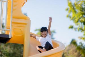 kind spelen Aan buitenshuis speelplaats. kinderen Speel Aan school- of kleuterschool tuin. actief kind Aan kleurrijk glijbaan en schommel. gezond zomer werkzaamheid voor kinderen. weinig meisjes beklimming buitenshuis. foto