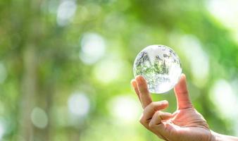 kristal bal gebruikt net zo een vertellen voorwerp. natuur park met bomen in de achtergrond. hand- voor milieu, sociaal, en bestuur in duurzame en ethisch bedrijf Aan groen achtergrond. foto