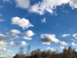 structuur van de blauw lucht met wit pluizig luchtig pluizig licht schoon regen zacht wolken tegen de achtergrond van een groen Woud. de achtergrond foto