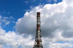 een groot hoog niet-ecologisch metalen ijzer pijp voor de emissie van rook gas- Bij de petrochemisch chemisch raffinaderij industrieel raffinaderij tegen de achtergrond van de blauw lucht foto