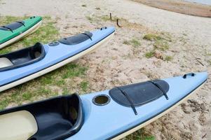 een veel van blauw en groen kano kajaks met voorkant onderdelen van de neuzen voor water sport, zwemmen liggen Aan de strand Aan de strand foto