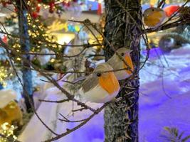 Kerstmis boom decoratie. speelgoed- vogel zit om een Afdeling boom in een fee Woud Aan wazig Kerstmis achtergrond. de concept van nieuw jaar en kerstmis. feestelijk decoratie foto