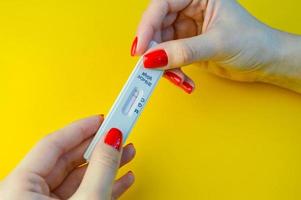 coronavirus test Aan een geel, helder achtergrond. medisch analyse. meisje met helder rood manicure Holding een negatief test voor antilichamen naar coronavirus foto