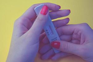 test voor coronavirus Aan een oranje achtergrond. medisch analyse. meisje met helder rood manicure Holding een test voor antilichamen naar coronavirus, bloed negatief foto