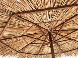structuur van een natuurlijk rietje droog strand zon paraplu gemaakt van hooi droog gras en takken Aan de strand tegen een blauw lucht Bij een rust uit toevlucht foto