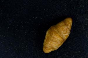 croissant geïsoleerd Aan zwart steen achtergrond foto