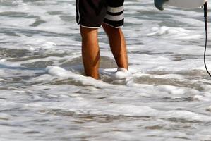 een Mens wandelingen blootsvoets Aan de zand door de zee foto