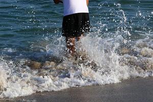 een Mens wandelingen blootsvoets Aan de zand door de zee foto