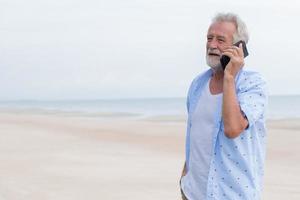 senior single Mens pratend Aan roeping gedurende vakantie Bij zee strand schoon ruimte voor tekst foto