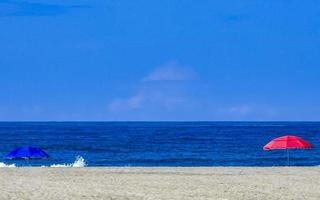 zonneschijn parasol golven en strand zand puerto escondido Mexico. foto