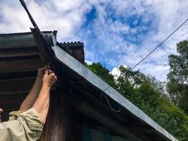 Mens reparaties de dak Bij een hoogte. fabricage in een houten huis. afdichting gaten, gaten in een woon- gebouw. dak monteur. vervaardiging van houten dak aan het bedekken foto