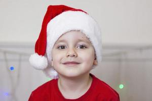 portret van een schattig jongen in een de kerstman claus hoed. grappig glimlachen kind. foto