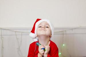 portret van een schattig jongen in een de kerstman claus hoed. grappig glimlachen kind. geschenken, speelgoed, vreugde, viering. foto