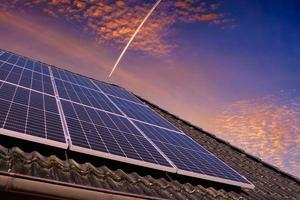 zonne- panelen produceren schoon energie Aan een dak van een woon- huis gedurende zonsondergang. foto