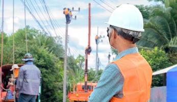 elektrisch ingenieur aan het kijken de werk van arbeiders foto