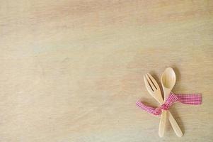 keuken gebruiksvoorwerpen. houten vork en lepel met rood kleding stof Aan houten achtergrond foto