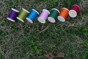 veelkleurig draden Aan groen gras voor naaien achtergrond foto