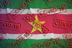 Suriname vlag en veel rood covid-19 postzegels. coronavirus of 2019-ncov virus concept foto
