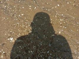 de schaduw van een volwassen Mens Aan de strand zand foto