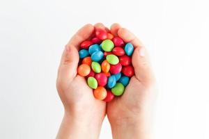 veelkleurig snoepjes in de handen van een kind Aan een wit geïsoleerd achtergrond foto