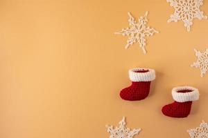 handgemaakt haken kous en wit sneeuwvlok Aan oranje pastel achtergrond. vrolijk Kerstmis en gelukkig nieuw jaar concept. foto