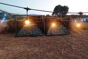 avond camping in de rijst- veld- had geoogst, net Woud en bergen in de achtergrond met licht lamp. foto