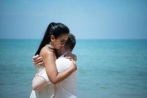 een jong wit Mens vragen voor een Aziatisch meisje naar trouwen met een diamant ring Aan een strand foto