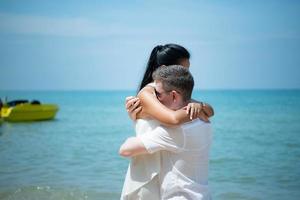 een jong wit Mens vragen voor een Aziatisch meisje naar trouwen met een diamant ring Aan een strand foto