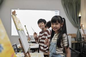 portret van Aziatisch kinderen op zoek Bij camera en glimlachen met acryl kleur afbeelding geschilderd Aan canvas in kunst klas en creatief aan het leren met talenten en vaardigheid Bij elementair school- studio onderwijs. foto