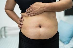 overgewicht aziatische vrouw toont dikke buik op kantoor. foto