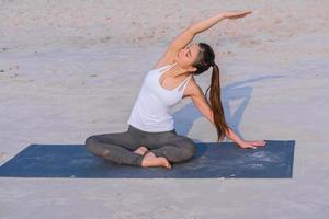 jong Aziatisch gezond vrouw aan het doen yoga oefening Aan de strand in de ochtend. foto