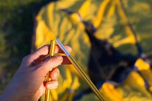 aluminium montagebogen voor de installatie van een toeristische gele tent in de handclose-up. lichtgewicht uitrusting voor toerisme. buitenactiviteiten, montage-instructies, binnenlands ecotoerisme. kopieer ruimte foto